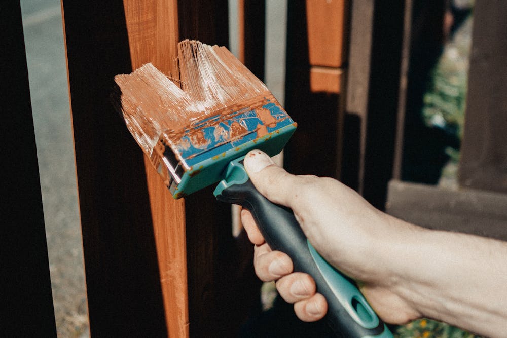 Applying a fresh coat of stain to a wood fence with a brush